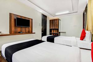a hotel room with two beds and a flat screen tv at Collection O 73565 J J Global Exotics Stays in Bangalore