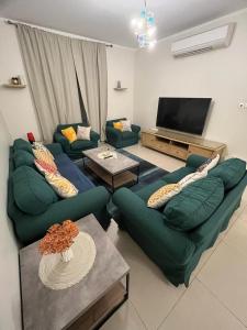 sala de estar con 2 sofás y TV de pantalla plana en King Abdullah Economic City Apartment - KAEC, en King Abdullah Economic City