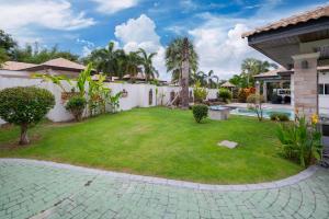 a backyard with a grassy yard and a house at Orchid Paradise Homes Villa in Hua Hin