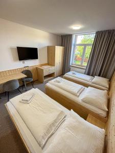 um quarto de hotel com três camas e uma secretária em Apartmánový byt em Valašské Meziříčí