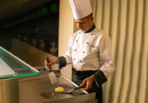 a chef preparing food in a restaurant kitchen at Hotel Continental Fuchu in Fuchu