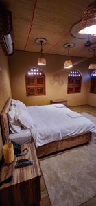 um quarto com uma cama grande e uma mesa de madeira em Aldar Inn em Nizwa
