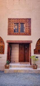 a building with two wooden doors and two potted plants at Aldar Inn in Nizwa