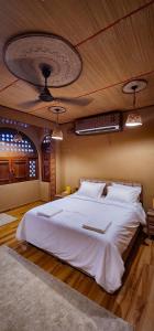 a bedroom with a large white bed with a ceiling at Aldar Inn in Nizwa