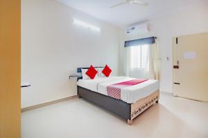 a bedroom with a bed with red pillows at OYO Flagship 77067 P N K Suites in Jālahalli