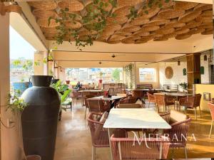 a restaurant with tables and chairs and a large vase at Hotel Meerana in Jaisalmer