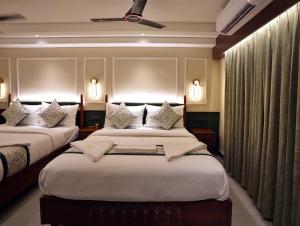 2 Betten in einem Hotelzimmer mit Vorhängen in der Unterkunft Hotel Sonar Bangla Puri in Puri