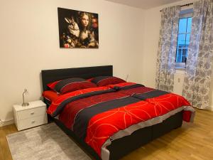 Un dormitorio con una cama roja con una pintura en la pared en Private Wohnung direkt im Zentrum, en Braunau am Inn