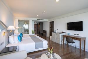 - une chambre avec un lit, un bureau et une télévision dans l'établissement 普吉岛-安达曼海滩海景度假酒店 Phuket-Andaman Beach Seaview Hotel, à Patong Beach