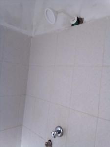 eine Dusche im Bad mit weißem Fliesenboden in der Unterkunft Gemütlich Green house in Mombasa