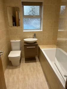a bathroom with a toilet and a sink and a bath tub at Spacious Central 2Bed Apartment in Wilmslow