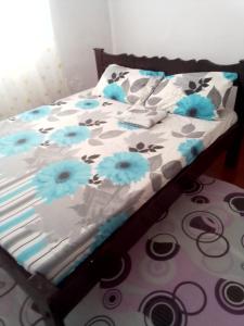 ein Bett mit blauen Blumen darauf in einem Schlafzimmer in der Unterkunft Gemütlich Green house in Mombasa