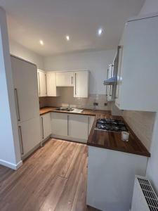 a kitchen with white cabinets and a wooden floor at Spacious Central 2Bed Apartment in Wilmslow