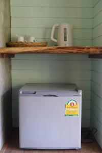 a small refrigerator in a room with a shelf at Koh Mak Living in Ko Mak