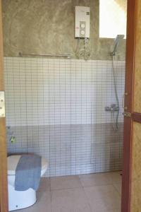 a tiled bathroom with a toilet and a shower at Koh Mak Living in Ko Mak