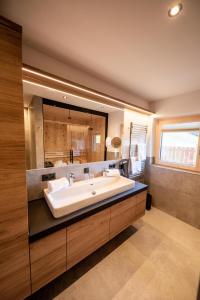 ein Badezimmer mit einem Waschbecken und einem großen Spiegel in der Unterkunft Studio Weitblick in Saalbach-Hinterglemm