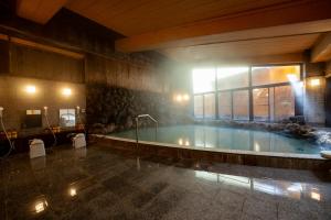 una grande piscina in un edificio con finestra di KAMENOI HOTEL Kusatsu Yubatake a Kusatsu