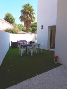 a patio with a table and chairs and a palm tree at Duplex 5 p 40m2 jardin de 50m2 in Six-Fours-les-Plages