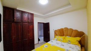 1 dormitorio con 1 cama y armario de madera en Residence GermanoTech, Bonamoussadi,Logbessou appartement meublé 2ch,1salon eau chaude,Wifi,parking,virgile,menagere,canalsat, en Douala