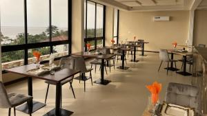 a restaurant with tables and chairs and large windows at SKY KENAKO HOTEL in Kribi