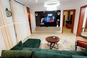 sala de estar con sofá verde y TV en Prive Apartments Katampe Extension 3bed, en Abuja