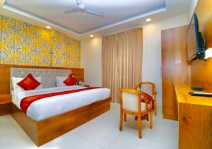 a bedroom with a bed and a desk and a television at Hotel Glace Airport Stay Near IGI Airport in New Delhi +17 photos