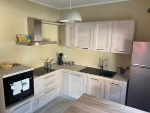 eine Küche mit weißen Schränken, einer Spüle und einem Kühlschrank in der Unterkunft Lisonino House in SantʼAngelo Lodigiano