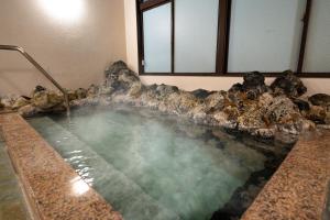 a large pool of water in a room with rocks at KAMENOI HOTEL Kusatsu Yubatake in Kusatsu