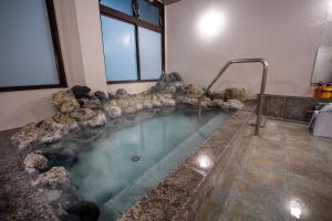a jacuzzi tub in a room with rocks at KAMENOI HOTEL Kusatsu Yubatake in Kusatsu