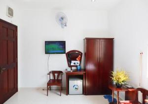 um quarto com uma televisão, uma cadeira e um armário em Khách sạn Song Anh em Ho Chi Minh