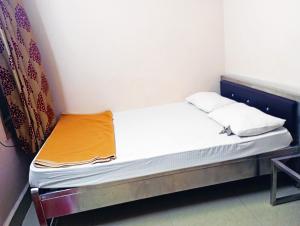 a small bed in a small room with white sheets at Jayalaxmi Comforts in Hubli