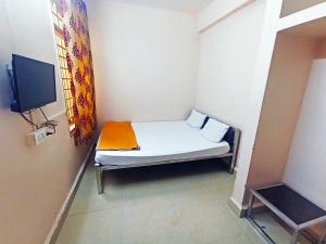 a small bed in a room with a tv at Jayalaxmi Comforts in Hubli