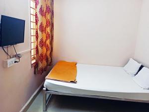 Habitación pequeña con cama y TV. en Jayalaxmi Comforts, en Hubli