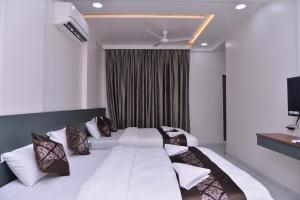 ein Schlafzimmer mit einem großen weißen Bett mit Kissen in der Unterkunft HOTEL D SQUARE . in Shirdi