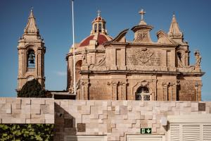 un antiguo edificio con una torre de reloj delante de él en Palazzo Castagna Boutique Hotel en Għaxaq