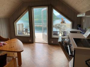 a kitchen with large windows and a view of the water at Leilighet i rorbu på Kaldfarnes - Yttersia Senja in Kaldfarnes