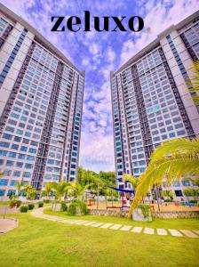 deux grands bâtiments dans un parc avec un palmier dans l'établissement #1 Jesselton Quay City Pads Seaview by Zeluxo, à Kota Kinabalu