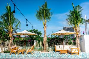 a patio with chairs and umbrellas and palm trees at Mia Luxury Villa Bình Châu in Xuyên Mộc