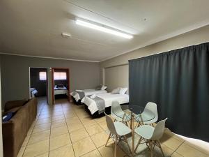 a hotel room with two beds and a table and chairs at 1 on Titania in Polokwane
