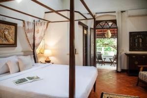 Lamrin Ucassaim Goa A 18th Century Portuguese Villa في Moira: غرفة نوم مع سرير وغرفة معيشة