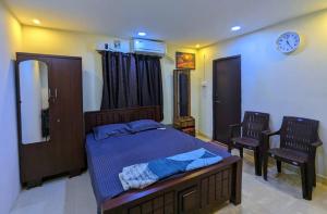 a bedroom with a bed and two chairs and a clock at GKV Service Apartment Saligramam in Chennai