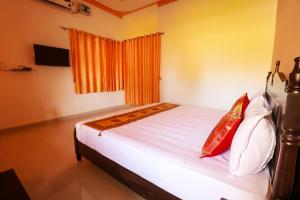 sypialnia z łóżkiem z białą pościelą i czerwonymi poduszkami w obiekcie AKSHAY VALLEY w mieście Kama