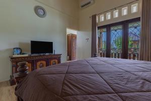 a bedroom with a bed and a tv and a window at Bait Nahwa in Mataram