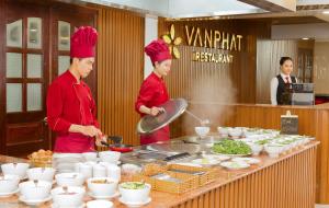 zwei Köche stehen in einer Küche und bereiten Essen zu in der Unterkunft Van Phat Riverside Hotel in Cần Thơ