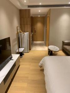 1 dormitorio con 1 cama, TV y sofá en Slow Apartment, en Guangzhou
