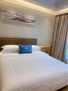 1 dormitorio con cama blanca grande y almohada azul en Slow Apartment, en Guangzhou