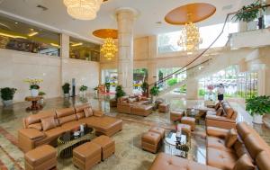 a lobby with brown leather couches and chandeliers at Van Phat Riverside Hotel in Can Tho