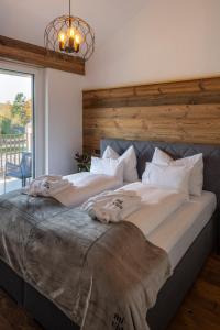 ein großes Bett mit weißer Bettwäsche und Kissen darauf in der Unterkunft RiverVista Apartments by mi_vida in Bad Waltersdorf