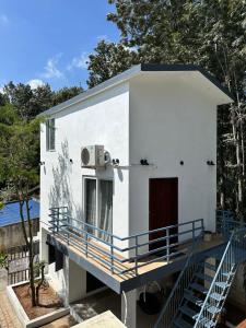 a small white house with a porch and stairs at Sharma Nivas Holiday Homestay in Yelagiri