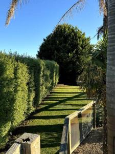 un jardín con setos y una valla en un soleado en Relax, Resort Style, en Rosebud